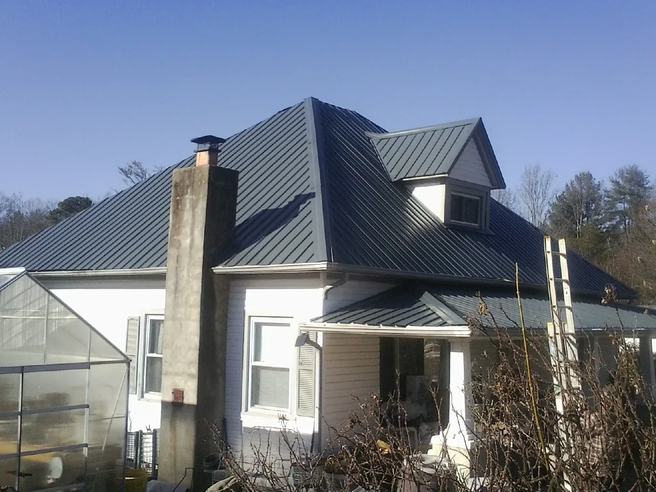 Dark blue standing seam metal roof on a white farmhouse with dormer — Slate & Tile Roof Repair by Roofing Brothers in Woodville