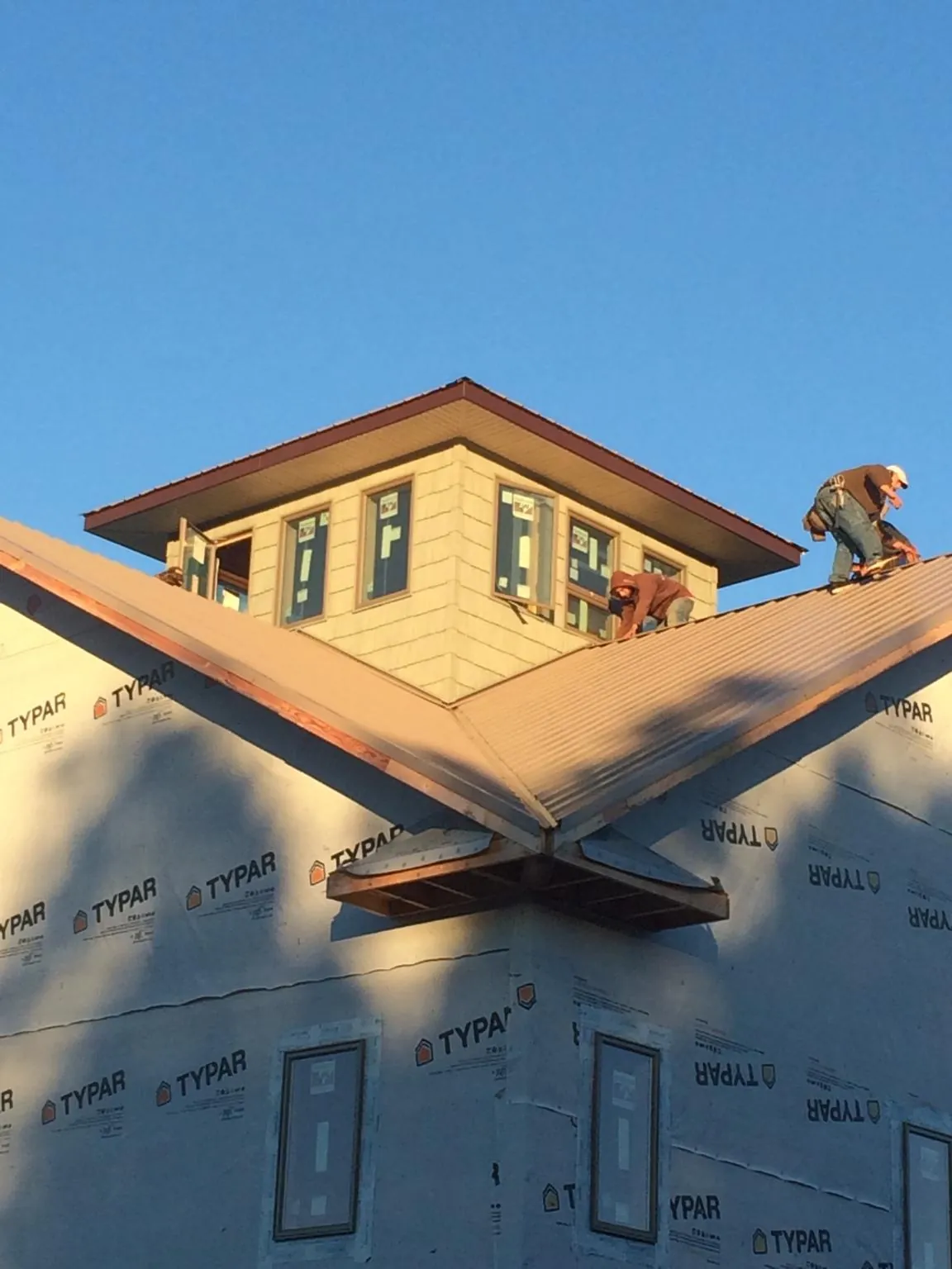 Roofers working around a rooftop cupola on a new metal roof at sunset — Roof Waterproofing in Woodville by Roofing Brothers